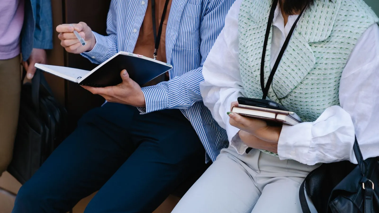 Peserta pertemuan memegang buku catatan dan pena sambil berdiskusi